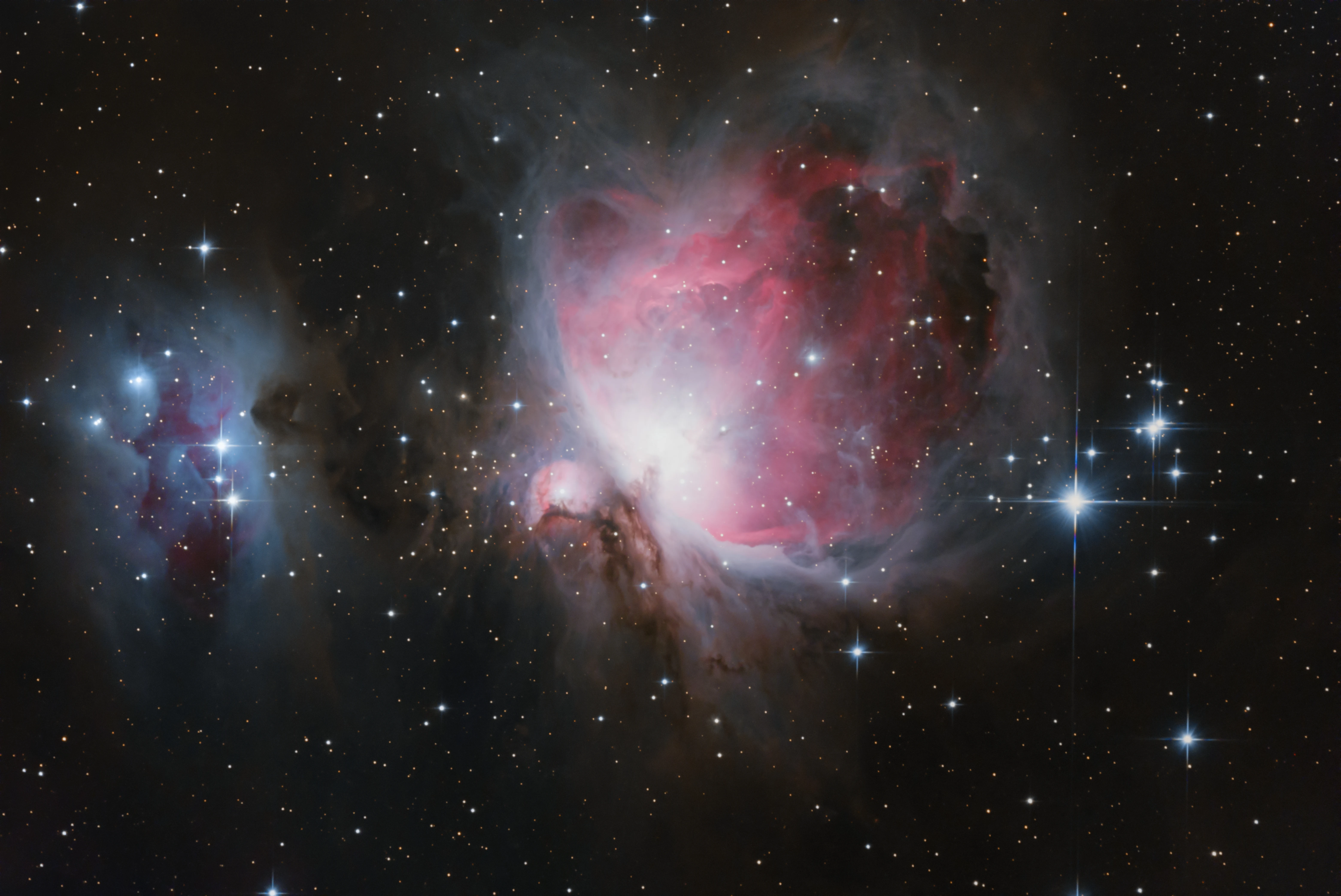 The Orion Nebula glowing pink and violet amid dark surrounding dust