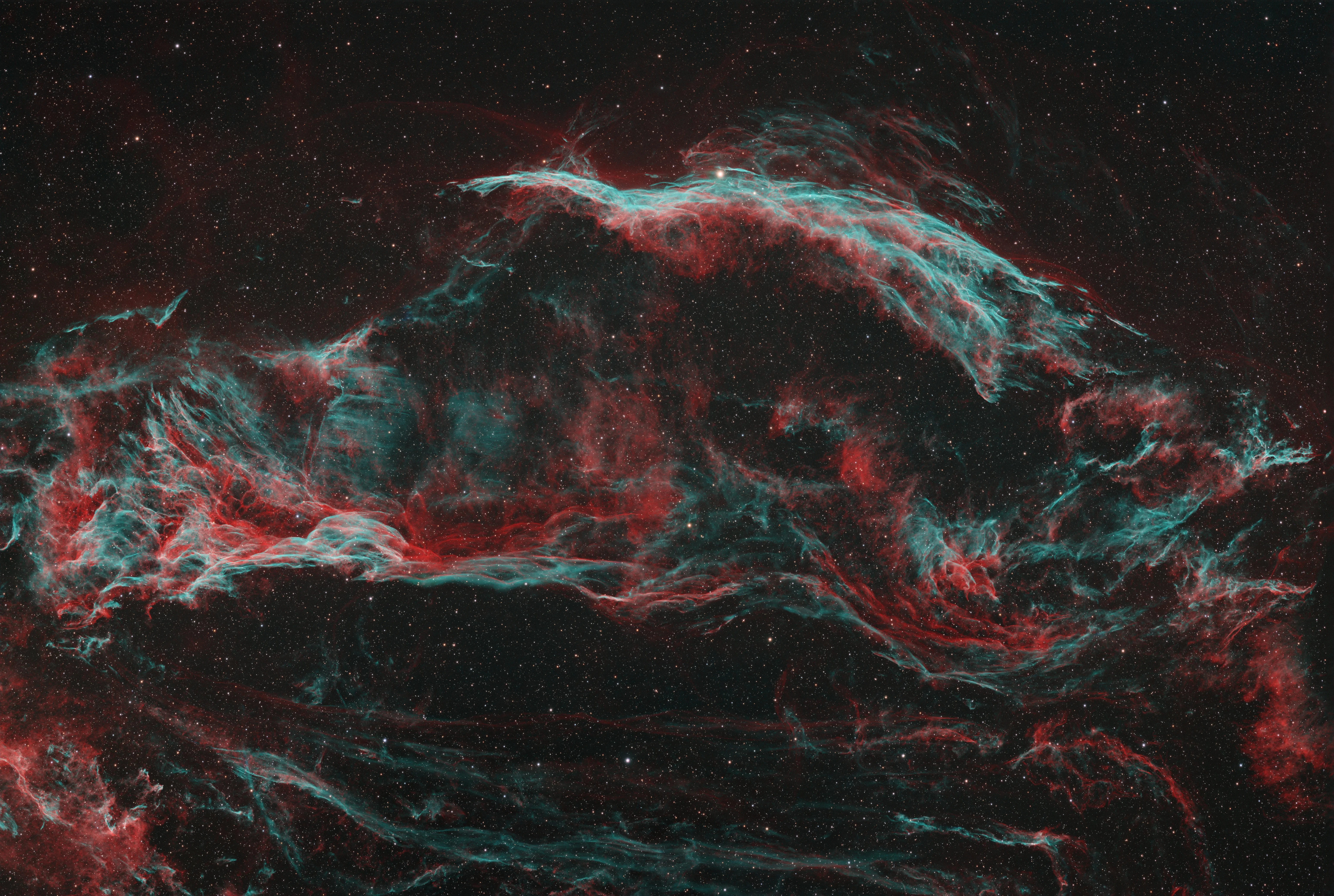Fine red and blue filaments of the Veil Nebula crossing a dark star field